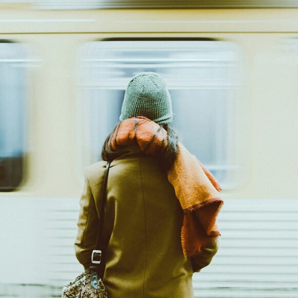 Young New Yorker walking past a produce stand with a tote bag, symbolizing budget living and shopping local in NYC